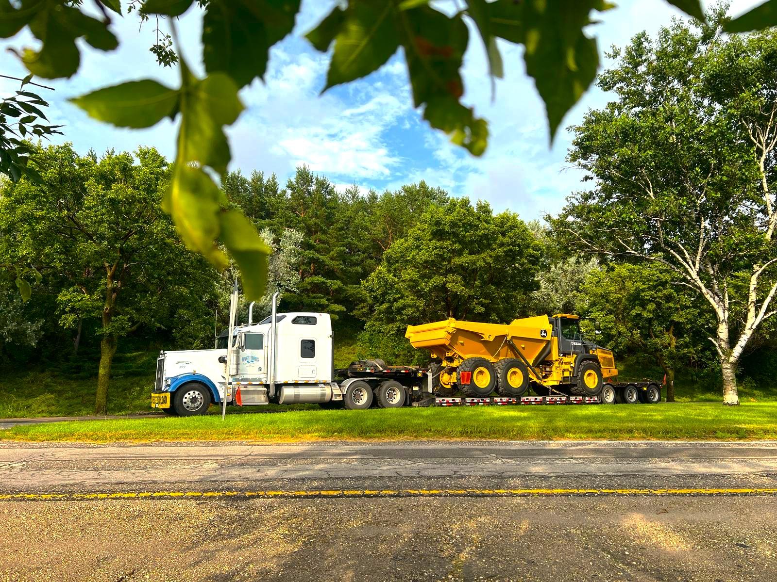 Yellow articulated dump truck loaded on a River Trails Transport RGN double drop trailer