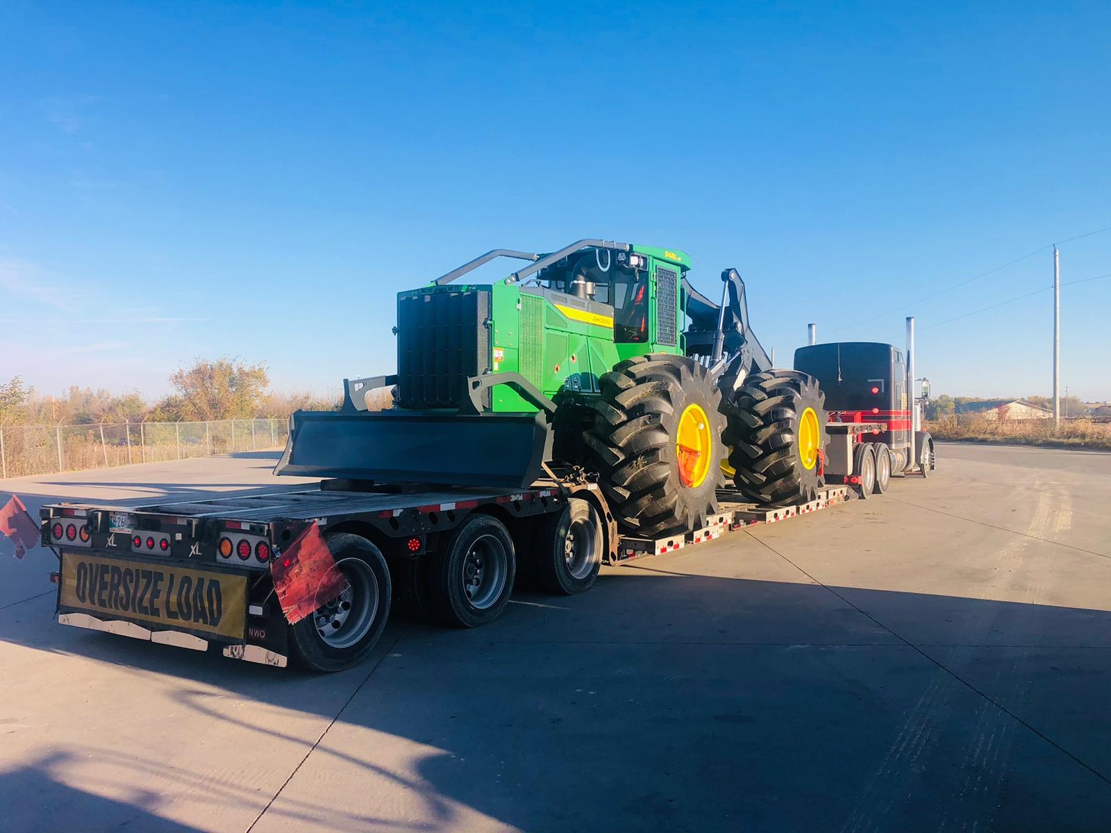 John Deere skidder loaded on the River Trails Transport RGN double drop trailer with oversize-load placard